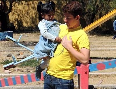 Volontari aiutano un bambino nel progetto di ippoterapia Volontari con un bambino per il progetto di terapia equestre in Argentina