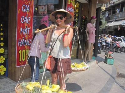Viaggi di volontariato in Vietnam Volontaria trasporta la frutta nel tipico modo vietnamita